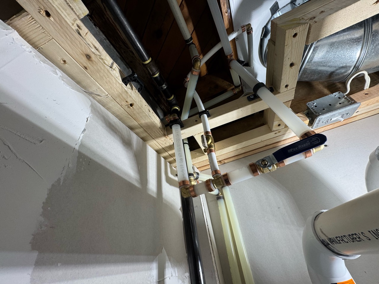 Water piping and valves routed through a confined space beneath framing